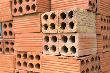 Texture of pile red clay bricks on construction site, close up