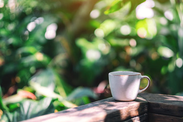 A mug of hot coffee on wooden balcony in the garden