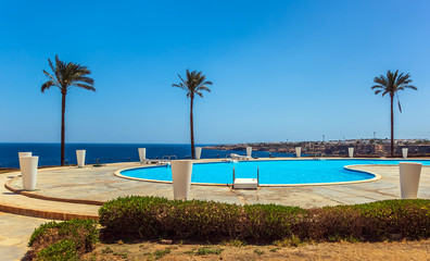 Fototapeta na wymiar Tropical palm tree resort at swimming pool landscape.