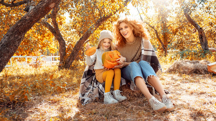 Young adult mother and daughter looking at carved pumpkin with smoke