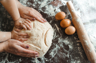 Mains de mère et de fils pétrissant une pâte ensemble. Les mains de la mère et de l& 39 enfant préparent la pâte avec de la farine sur une table en bois sombre. Fond de boulangerie. Concept de cuisine.