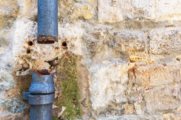 Broken downspout drainage pipe damaged exterior wall. Broken and damaged water pipe or drainpipe. Building exterior wall with green mold as result of water leak.