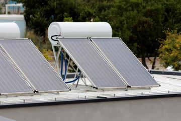 Brand new solar panels for water heating installed on roof of local tourist resort surrounded with...