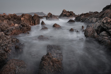 Motion blur waves over the rocks on the coast