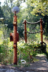 Rusted metal poles with holders and strong fishing rope between surrounded uncut grass tree branches on warm sunny summer day