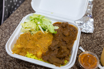 Chicken curry and ramp curry with yellow rice in a white plastic container