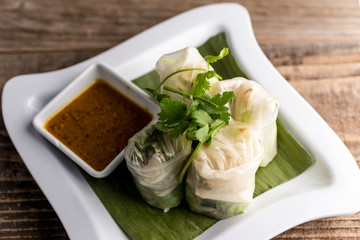 Shrimp Udang Roll with basil, bean sprouts, and peanut dipping sauce. Served on a reclaimed wood table.
