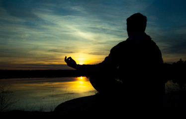 Silhouette of a meditating man . Meditation as a way to relax.