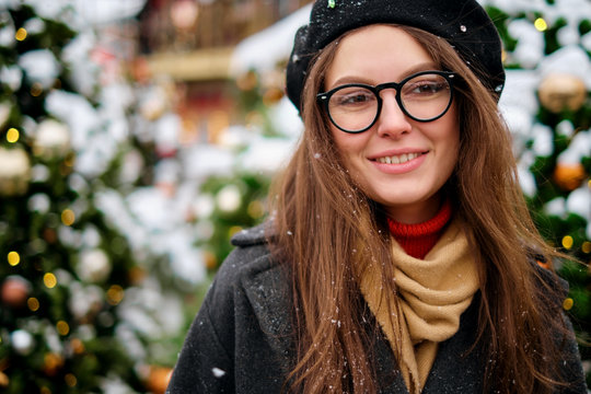 Close-up portrait of happy girl in beret enjoying winter moments. Outdoor photo of long-haired laughing lady in glasses having fun in snowy morning on blur nature background.