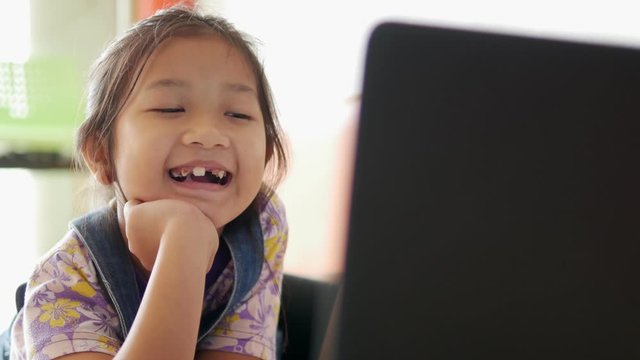 A young Asian girls is is lying flat on the floor, watching and enjoying  fun social media by using laptop.