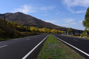 The black highway against the mountains and the cloudy sky.