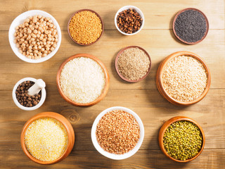 Rice, corn flakes, allspice, mung bean, fenugreek, buckwheat, cumin, chick pea, cloves oat on brown wooden background. Indian cuisine, ayurveda, naturopathy, modern apothecary concept