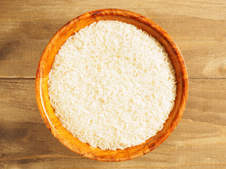 Rice in bamboo bowl on brown wooden background. Indian cuisine, ayurveda, naturopathy, modern apothecary concept