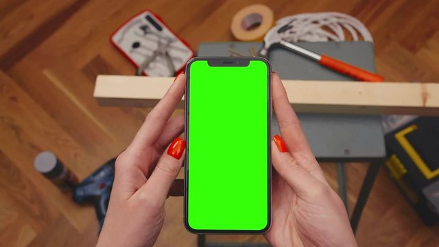 Woman watches video with advice on how to do repairs in house on smartphone