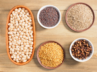 Mung bean, mustard seeds, fenugreek, cumin, cloves on brown wooden background. Indian cuisine, ayurveda, naturopathy, modern apothecary concept
