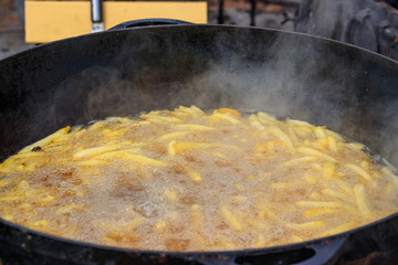 French fries cooking in a deep cast iron pan filled with oil