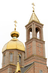 Fototapeta na wymiar Bottom view of the bell tower of the temple in honor of the Kazan Icon of the Mother of God in the village of New World of Donetsk region, Ukraine. ROC. Golden domes with a cross on the crown. Rainy