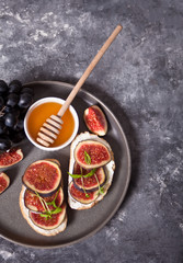 Sandwich with cream cheese, figs and honey served on the gray plate on the concrete background. Healthy food concept.
