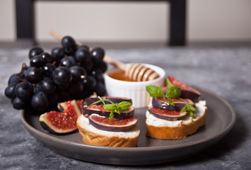 Sandwich with cream cheese, figs and honey served on the gray plate on the concrete background. Healthy food concept