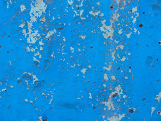 Wall with old blue paint. Peeling. Dark indentations.