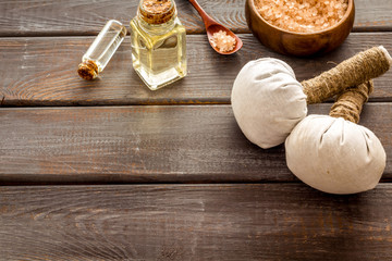 Massage thai herbal balls near spa accessories and orchids on dark wooden background copy space