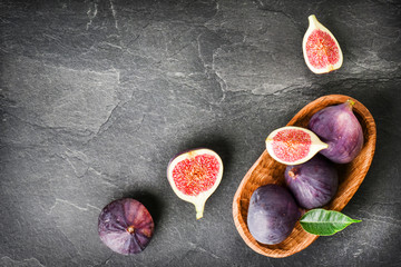 Fresh figs in wooden table on black background. Ripe citrus fig cut fruits on dark stone table from top view.