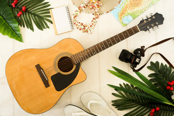 Camping or adventure trip scenery concept. Backpack, guitar, boots, belt, thermos and camera on wooden background captured from above (flat lay). Layout with free text (copy) space.