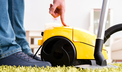 Man cleaning the floor carpet with a vacuum cleaner close up