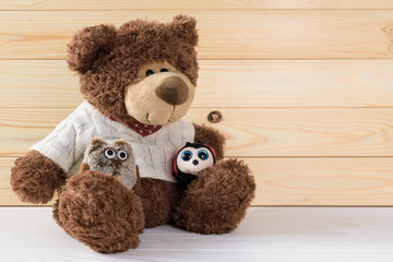 toy brown teddy bear sits on a white wooden table on a background of wooden boards