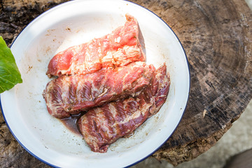 Pork rib marinade with Thai style herbs and spice in white bowl on wooden table background, Raw food, cooking meat