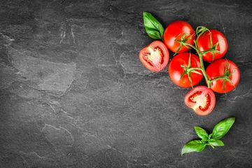 Fotobehang Fresh tomatoes with basil on dark stone table top view. Vegetables tomato with ketchup in bowl on board. © Milan
