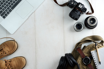 Camping or adventure trip scenery concept. Backpack, boots, belt, thermos and camera on wooden background captured from above (flat lay). Layout with free text (copy) space.