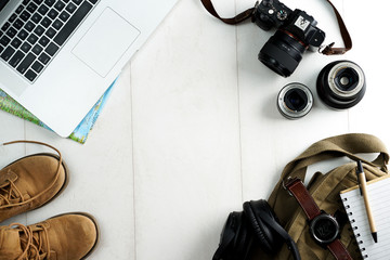 Camping or adventure trip scenery concept. Backpack, boots, belt, thermos and camera on wooden background captured from above (flat lay). Layout with free text (copy) space.