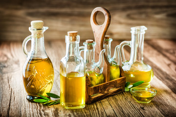 Fresh olives in rustic bowls on old wooden table. Virgin olive oil in clear glass bottles.