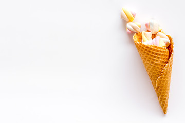 Sweet desserts. Marshmallows in ice cream waffle cone on white background top view space for text
