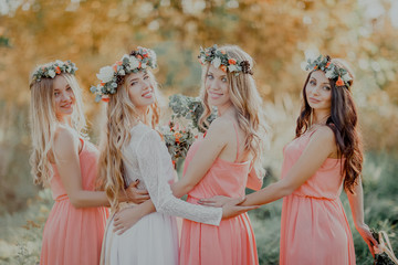 The bride with the bridesmaids looking at the camera. The autumn wedding. - obrazy, fototapety, plakaty