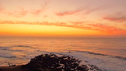 Fotobehang Oranje Orange sunrise over the fishing rocks at Ballito.  © Duncan