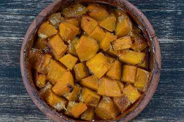 Baked yellow pumpkin with honey, olive oil and spices on a plate on the wooden table. Vegetarian food. Closeup