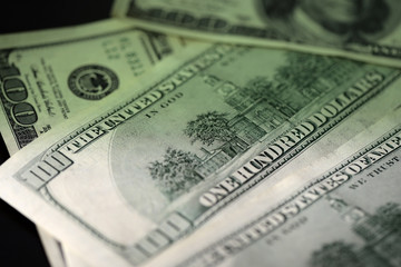 One hundred dollar bills on a dark surface close-up. Toned money background