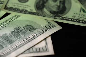 One hundred dollar bills on a dark surface close-up. Toned money background