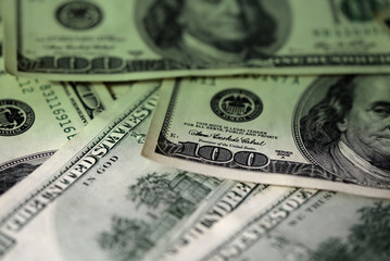 One hundred dollar bills on a dark surface close-up. Toned money background