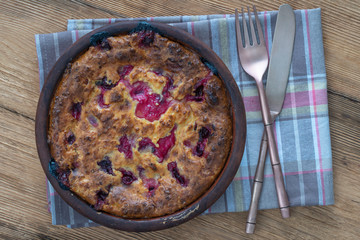 Sweet cottage cheese casserole with gooseberry and semolina on wooden table. Ceramic bowl with baked cottage cheese casserole