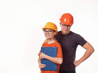 Emotional, young - a man with a woman foreman in yellow helmets with glasses and a folder in his hands on a white background