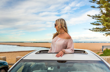 Fototapeta na wymiar Road trip to beach. Carefree woman in sunroof with views