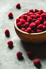 raspberries in wood bowl on gray table, vintage