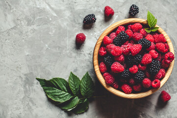 raspberries and blackberries in wood bowl on gray table, vintage