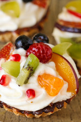 Beautiful cupcakes decorated with fresh fruits: grapes, peach, orange.