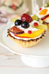 Beautiful cupcakes decorated with fresh fruits: grapes, peach, orange.
