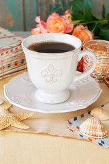 Cup of coffee, roses and vintage letters on the table.