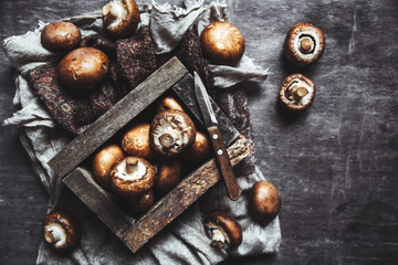 Royal mushrooms on a black background with a vintage board and a kitchen towel